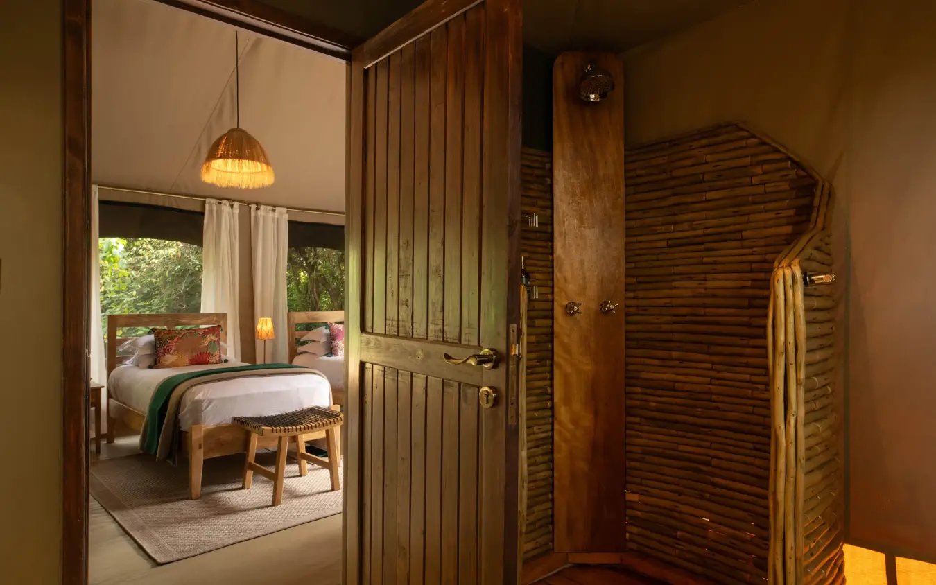 Bedroom interior with open wardrobe and natural wood finishes, Rekero Camp, Maasai Mara, Kenya