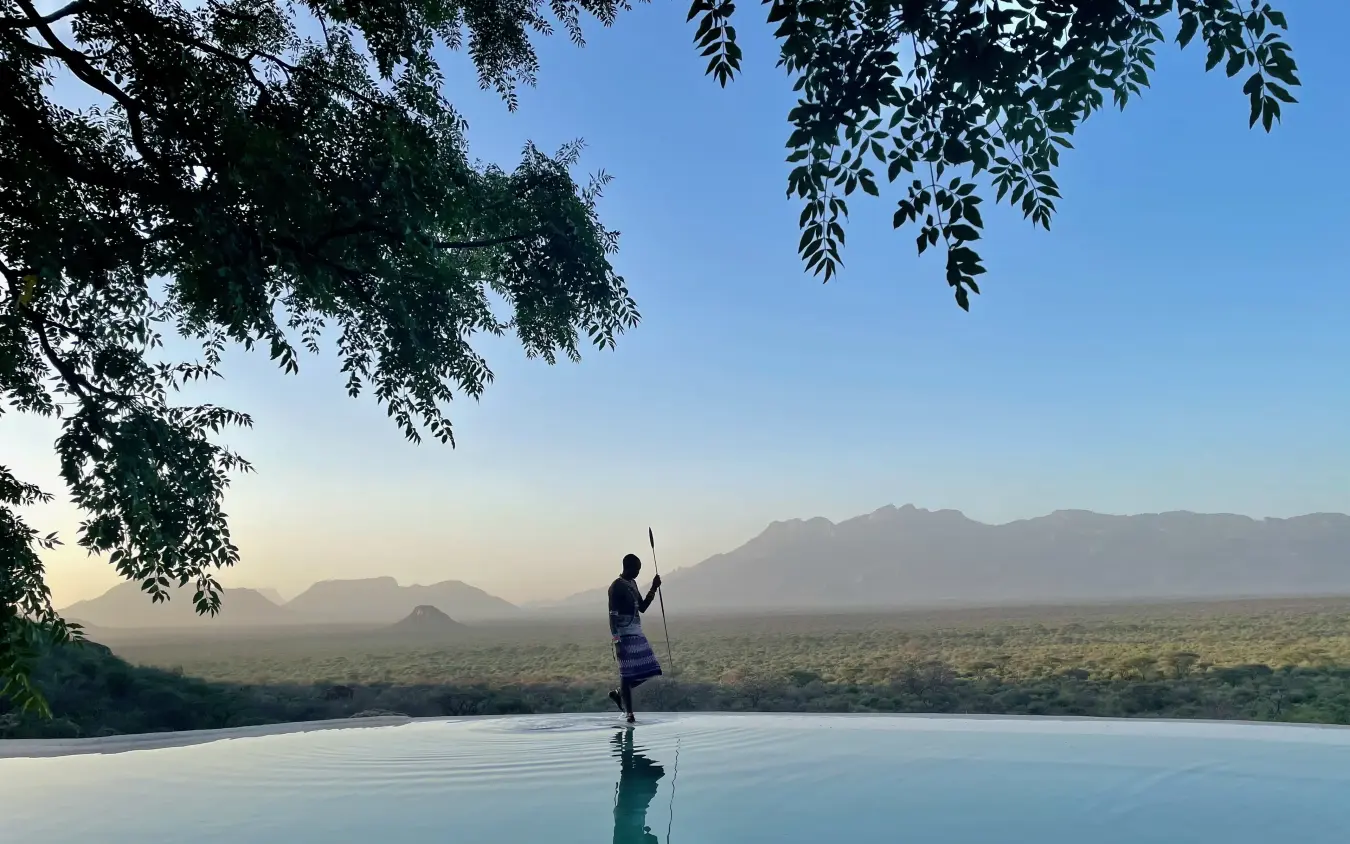 Guest at infinity pool overlooking savanna and mountains, Reteti House, Northern Kenya, Kenya