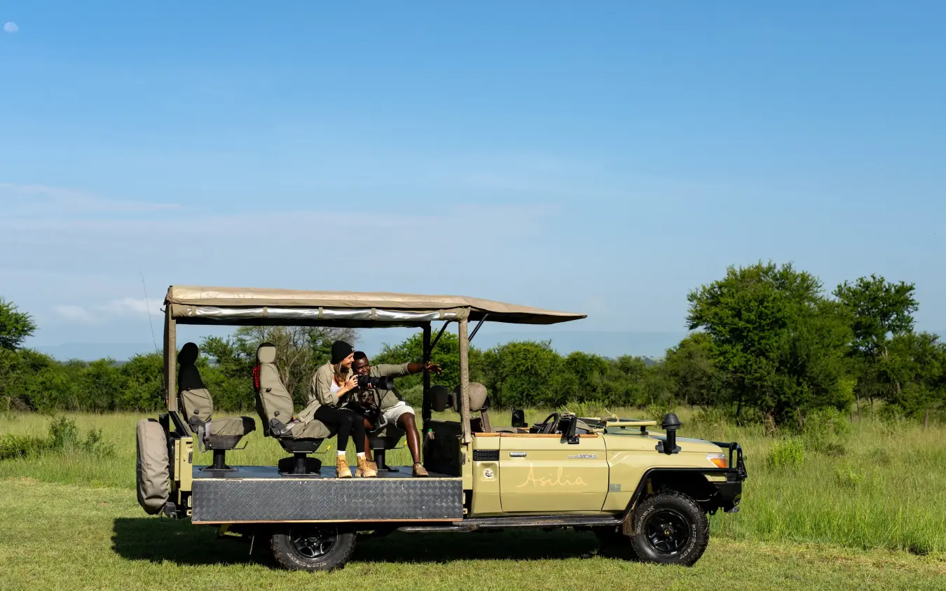 Safari vehicle with guests on game drive in grassland, The Retreats at Sayari Camp, Serengeti National Park, Tanzania