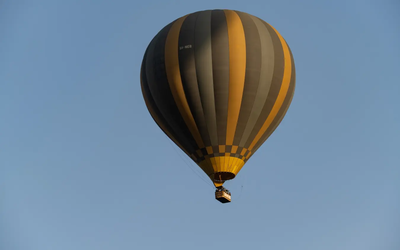 Hot air balloon floating above savanna landscape at dawn, The Retreats at Sayari Camp, Serengeti National Park, Tanzania