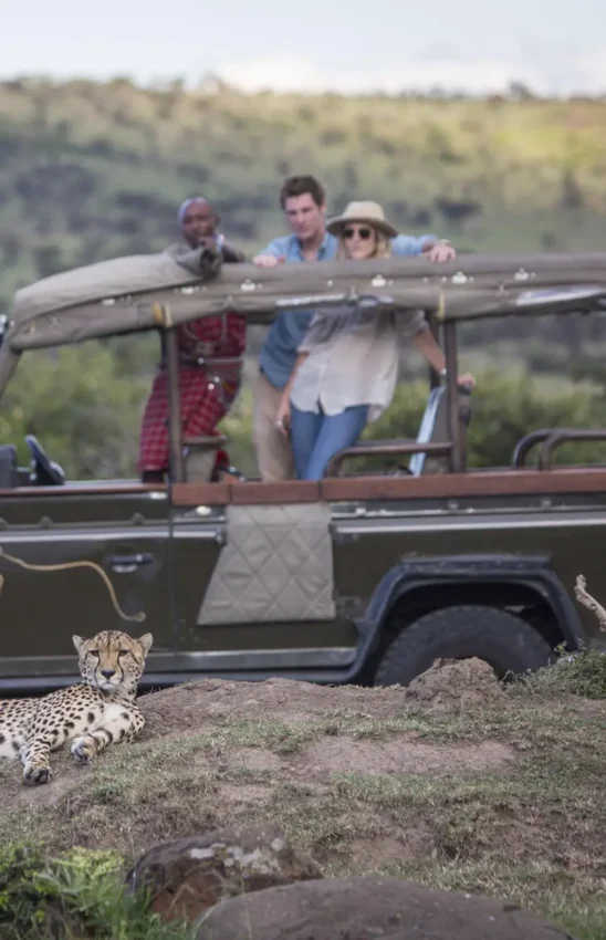 Safari vehicle with guests observing cheetah in natural habitat, Richard’s River Camp, Maasai Mara, Kenya