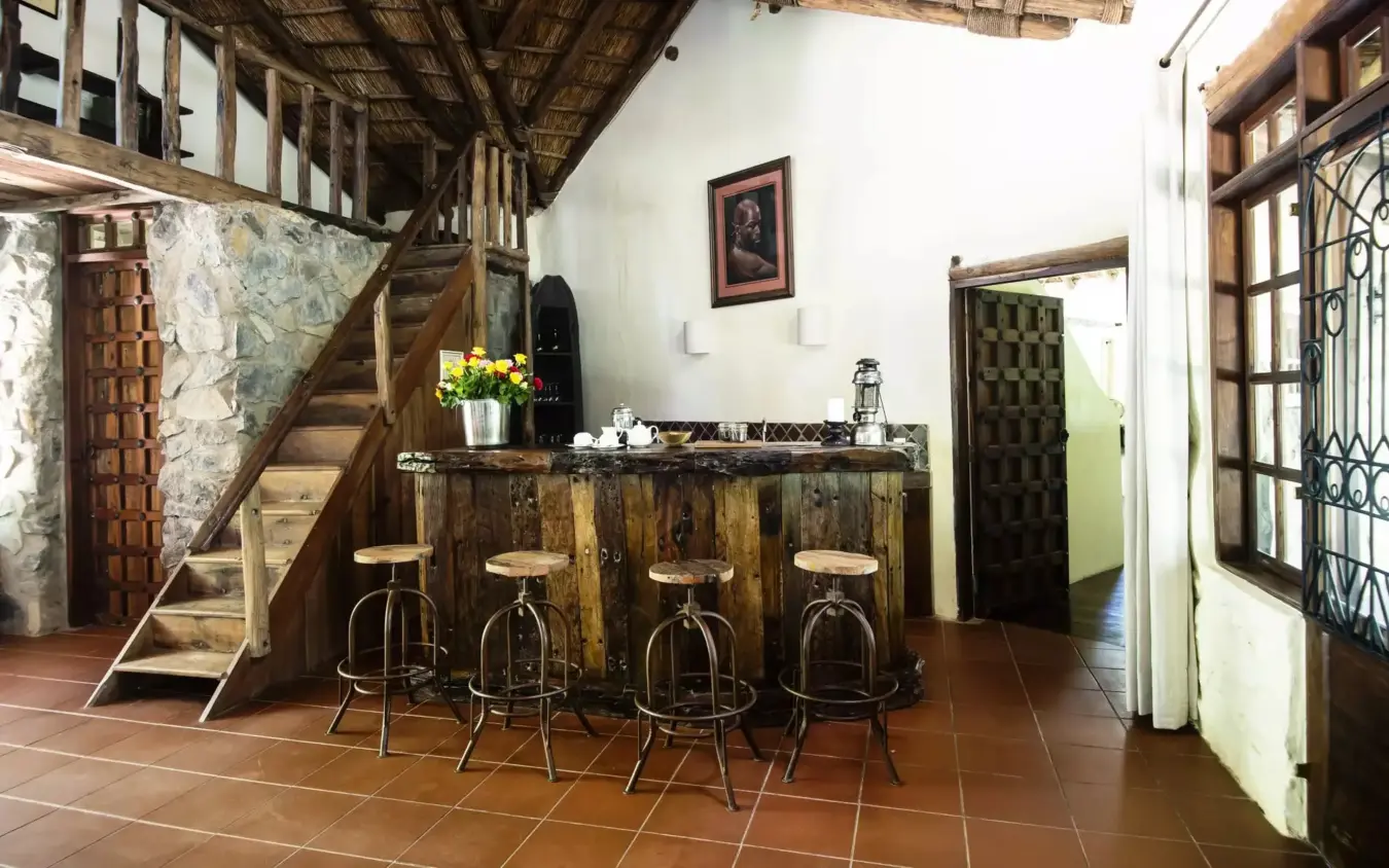 Interior bar and reception area with wooden counter and stools, Rivertrees Country Inn, Arusha, Tanzania