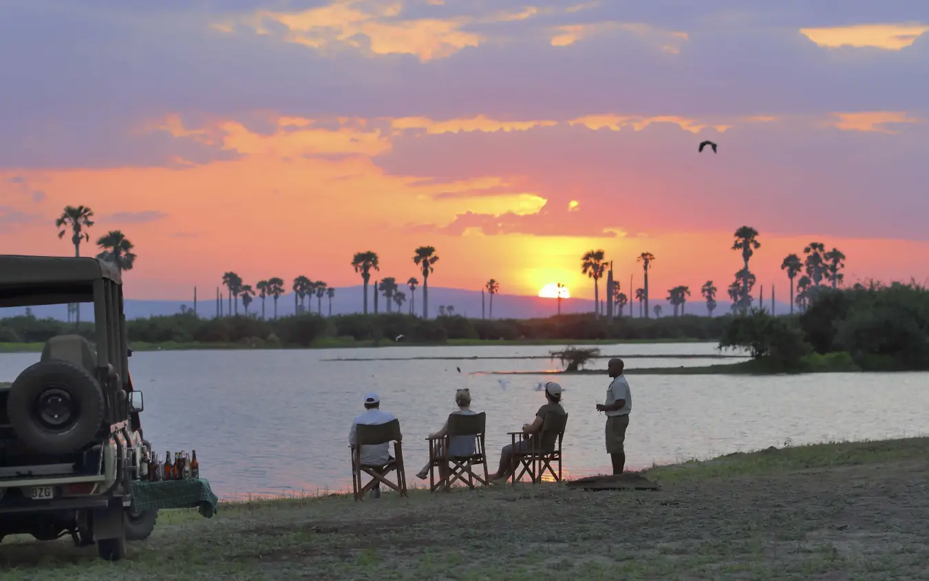 Guests watching sunset from riverbank chairs, Roho ya Selous, Nyerere National Park, Tanzania