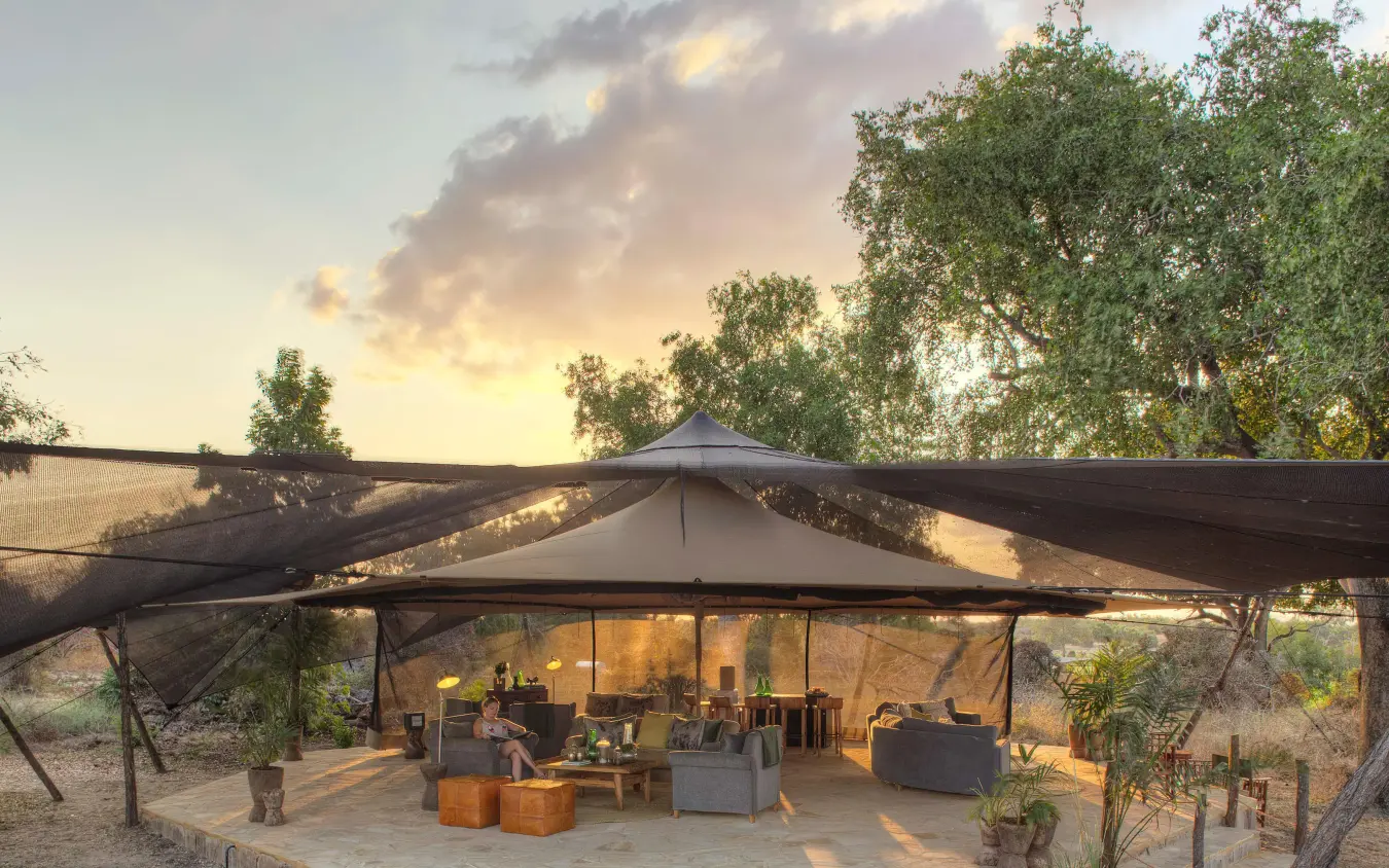 Open-sided canvas tent lounge at sunset with seating areas, Roho ya Selous, Nyerere National Park, Tanzania