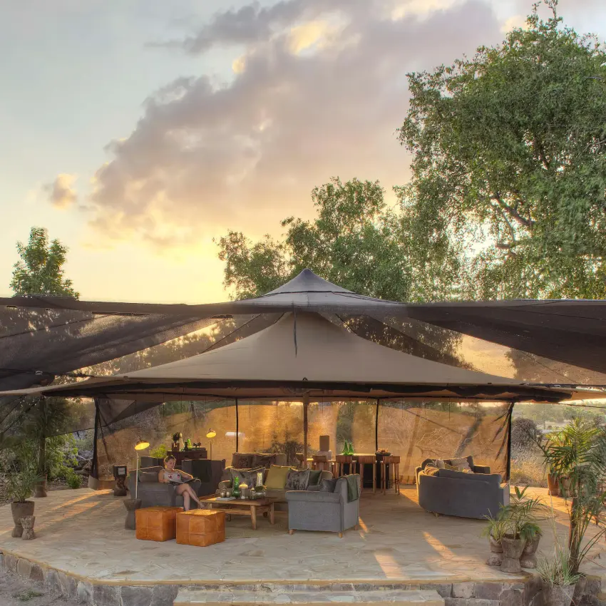 Open-sided canvas tent lounge at sunset with seating areas, Roho ya Selous, Nyerere National Park, Tanzania