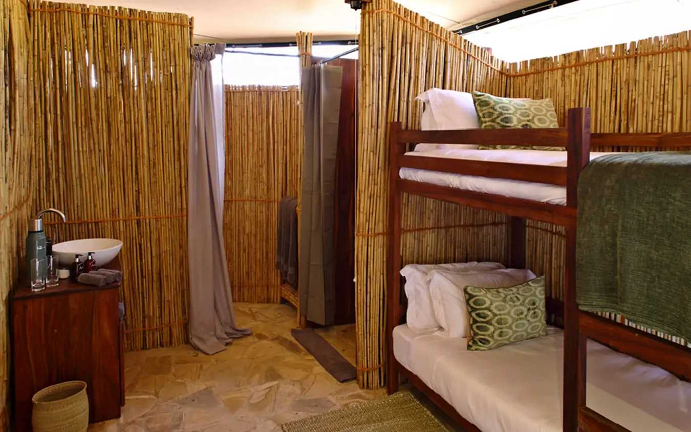 Bunk bed room with bamboo walls and private shower area, Roho ya Selous, Nyerere National Park, Tanzania