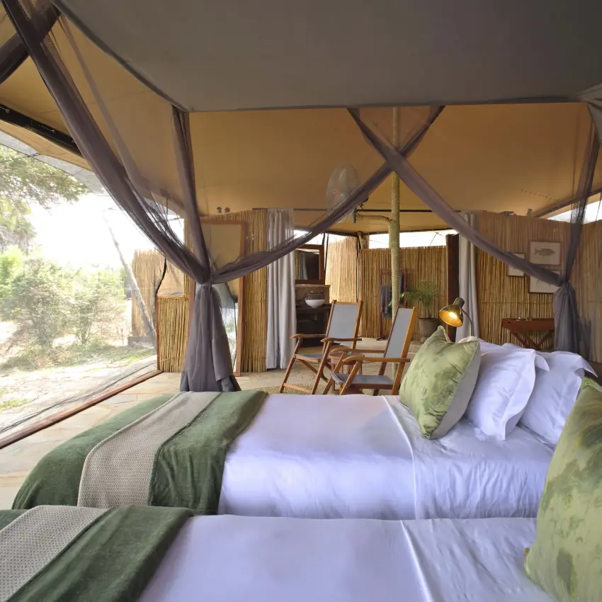 Luxury safari tent bedroom with large windows overlooking savanna, Roho ya Selous, Nyerere National Park, Tanzania
