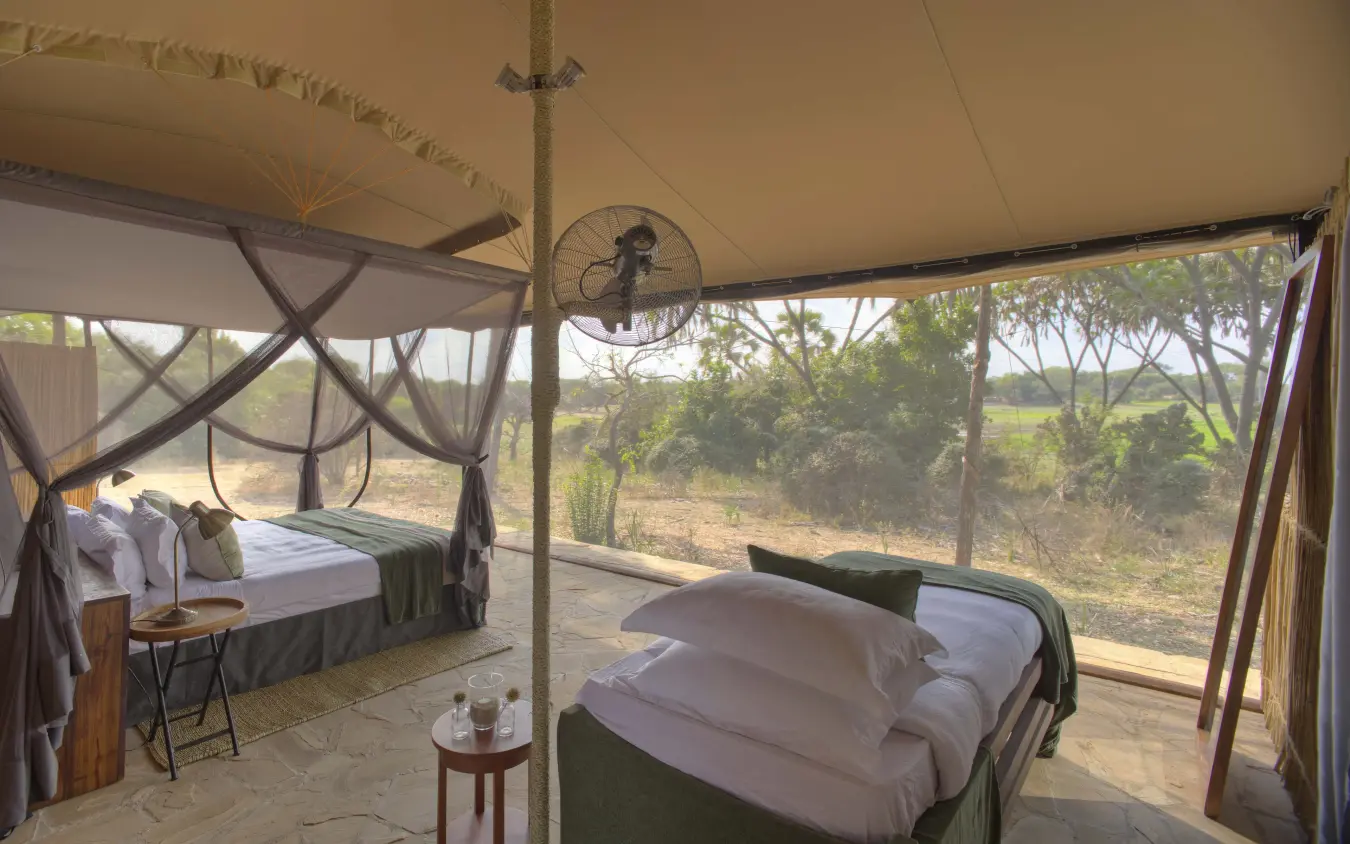 Safari tent bedroom with canopy beds and savanna view, Roho ya Selous, Nyerere National Park, Tanzania