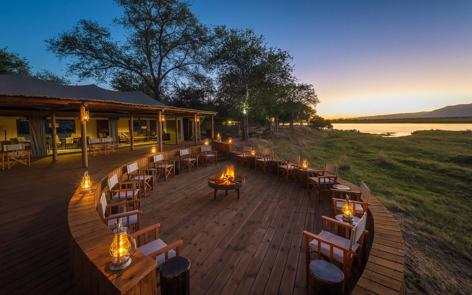 Wooden deck with seating area overlooking water at dusk, Ruckomechi Camp, Mana Pools, Zimbabwe