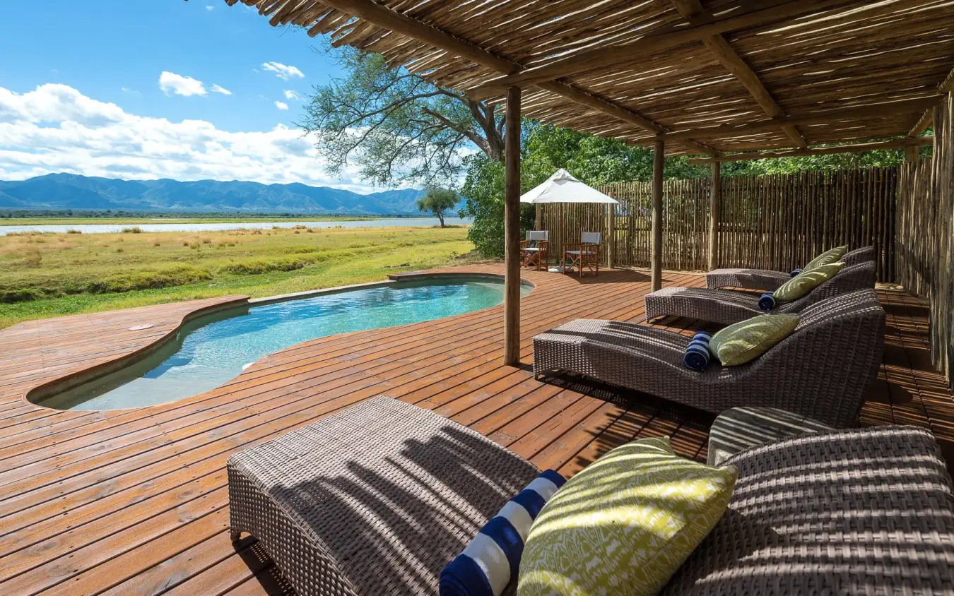 Wooden deck with loungers overlooking pool and savanna landscape, Ruckomechi Camp, Mana Pools, Zimbabwe