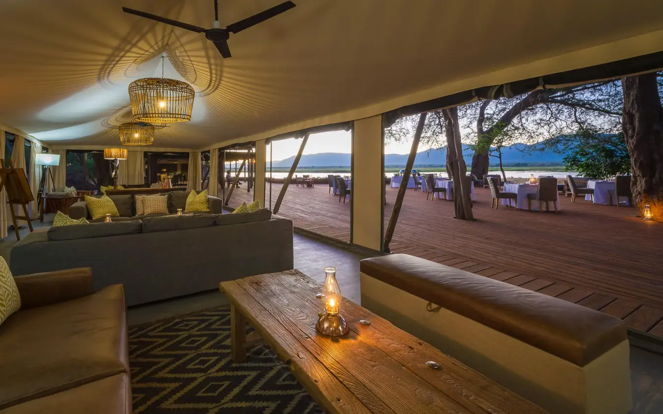 Open-air lounge with seating overlooking waterfront at dusk, Ruckomechi Camp, Mana Pools, Zimbabwe