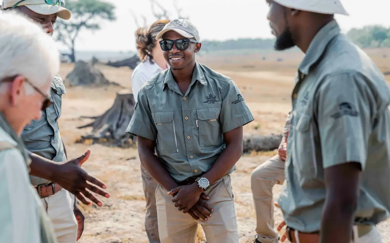 Guide leading interpretation walk with guests in bush landscape, Sable Valley Lodge, Hwange National Park, Zimbabwe
