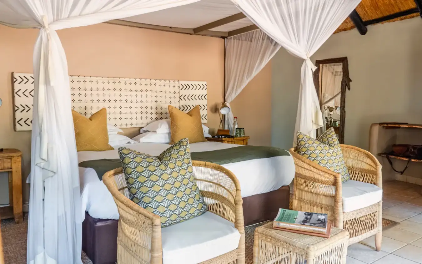 Four-poster bed with white curtains in luxury safari lodge bedroom, Sable Valley Lodge, Hwange National Park, Zimbabwe