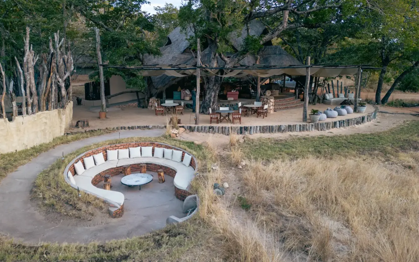 Sunken fire pit with curved seating overlooking safari lodge camp, Sable Valley Lodge, Hwange National Park, Zimbabwe