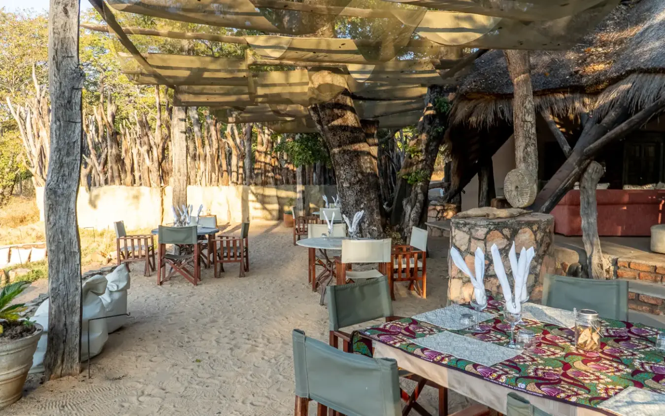 Open-air dining area with wooden furniture and thatched roof structures, Sable Valley Lodge, Hwange National Park, Zimbabwe