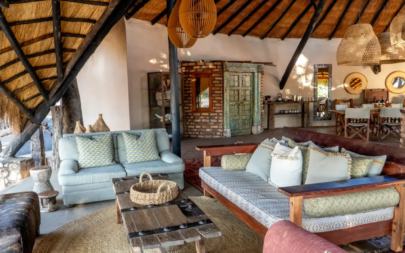 Open-plan lodge interior with thatch roof and wooden furnishings overlooking savanna, Sable Valley Lodge, Hwange National Park, Zimbabwe