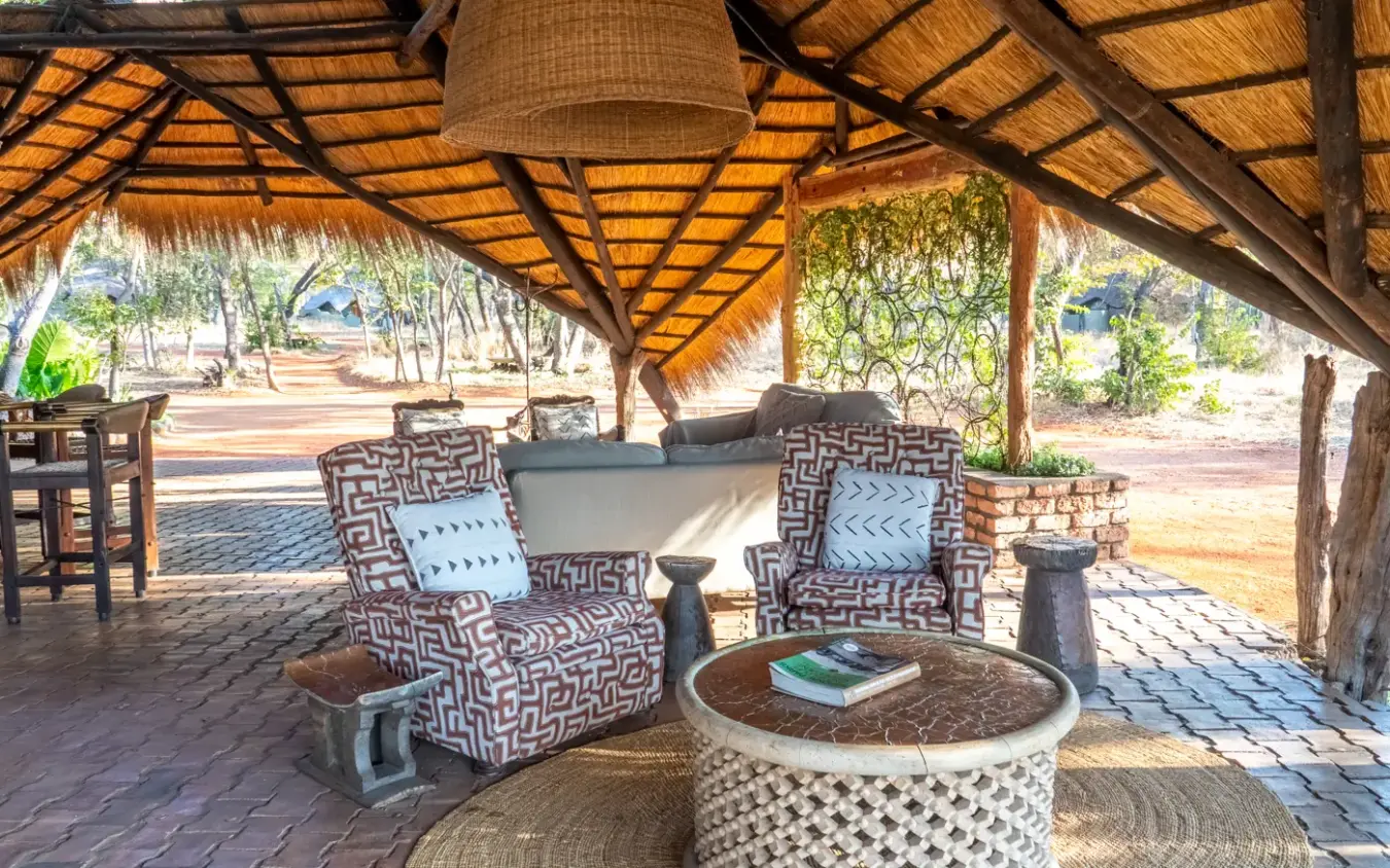 Thatched lounge pavilion with patterned armchairs and woven coffee table, Sable Valley Lodge, Hwange National Park, Zimbabwe