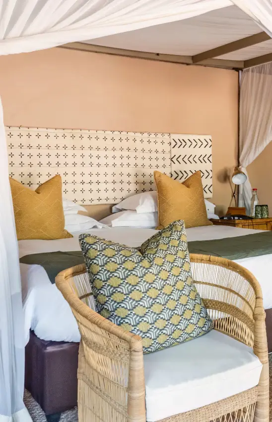 Luxury safari tent bedroom with canopy bed and rattan chair, Sable Valley Lodge, Hwange National Park, Zimbabwe