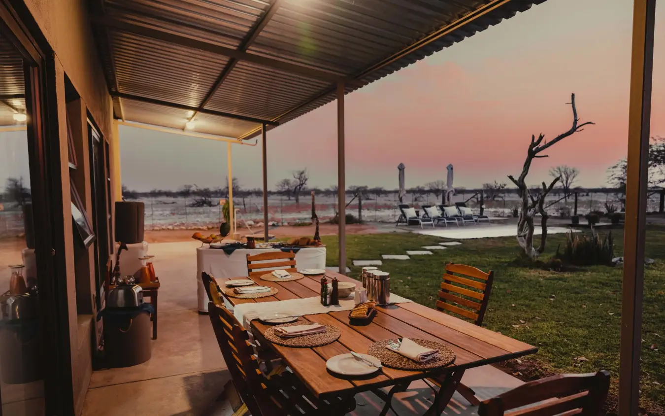 Outdoor dining deck overlooking wetland landscape at sunset, Safari House, Etosha National Park, Namibia