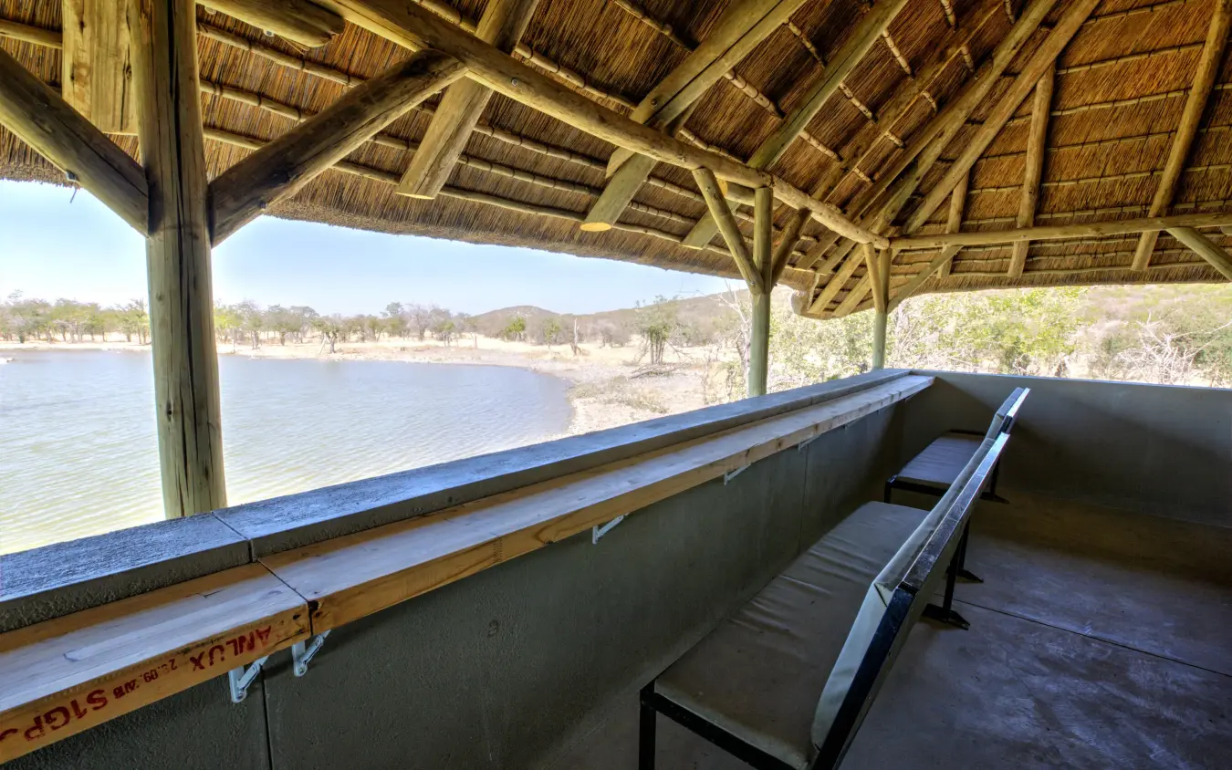 Covered observation deck overlooking calm waterhole and landscape, Safari House, Etosha National Park, Namibia