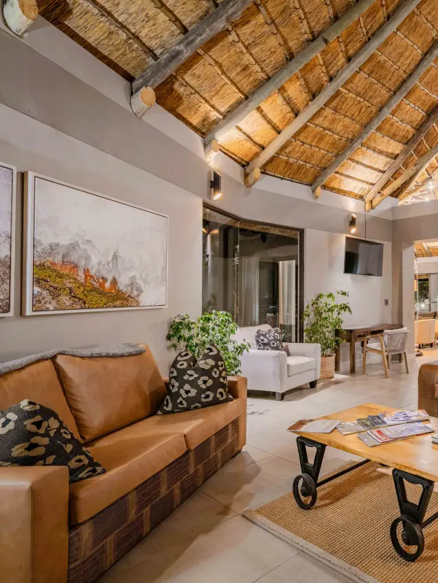 Open-plan lodge interior with thatched ceiling and leather furnishings, Safarihoek Lodge, Etosha National Park, Namibia