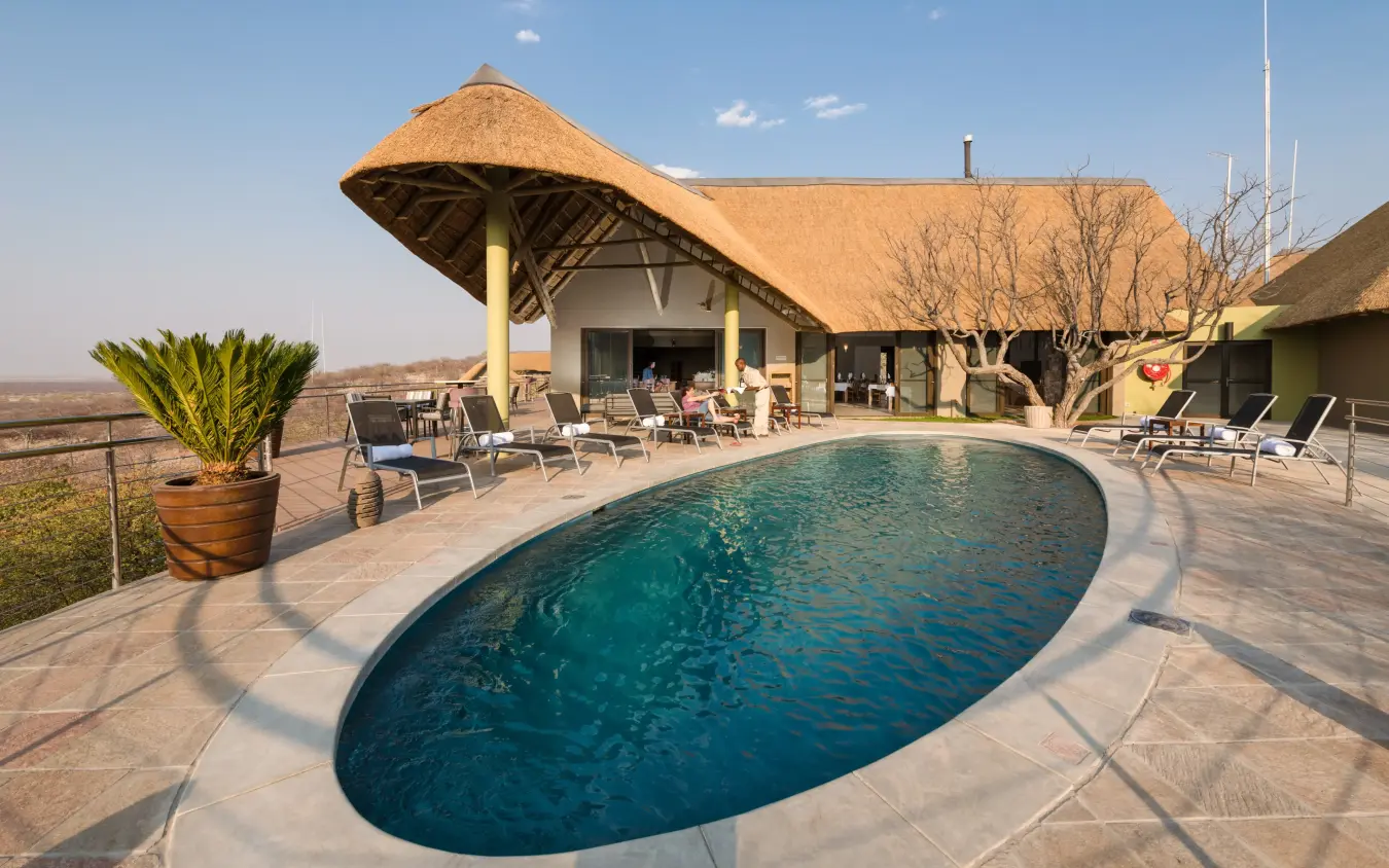 Luxury lodge with thatched roof and oval pool overlooking savanna landscape, Safarihoek Lodge, Etosha National Park, Namibia