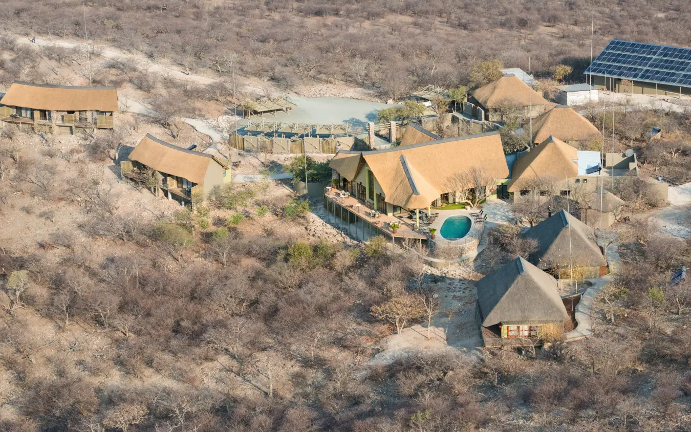 Aerial view of luxury lodge with thatched chalets nestled in arid bushland, Safarihoek Lodge, Etosha National Park, Namibia