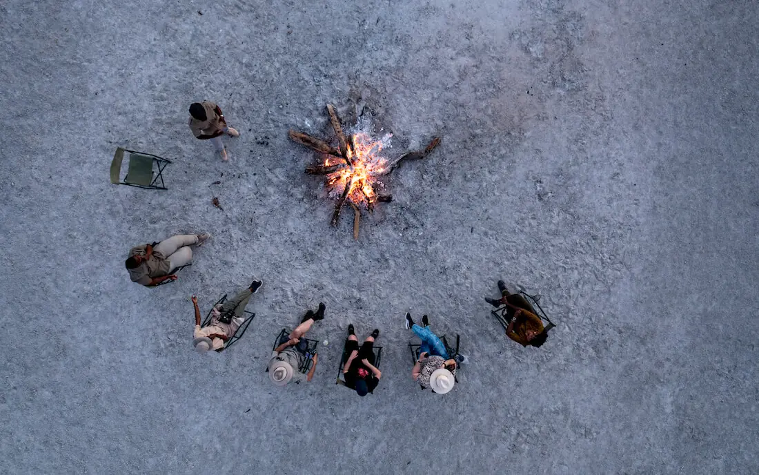 Aerial view of guests gathered around campfire at night, San Camp, Makgadikgadi Pans, Botswana