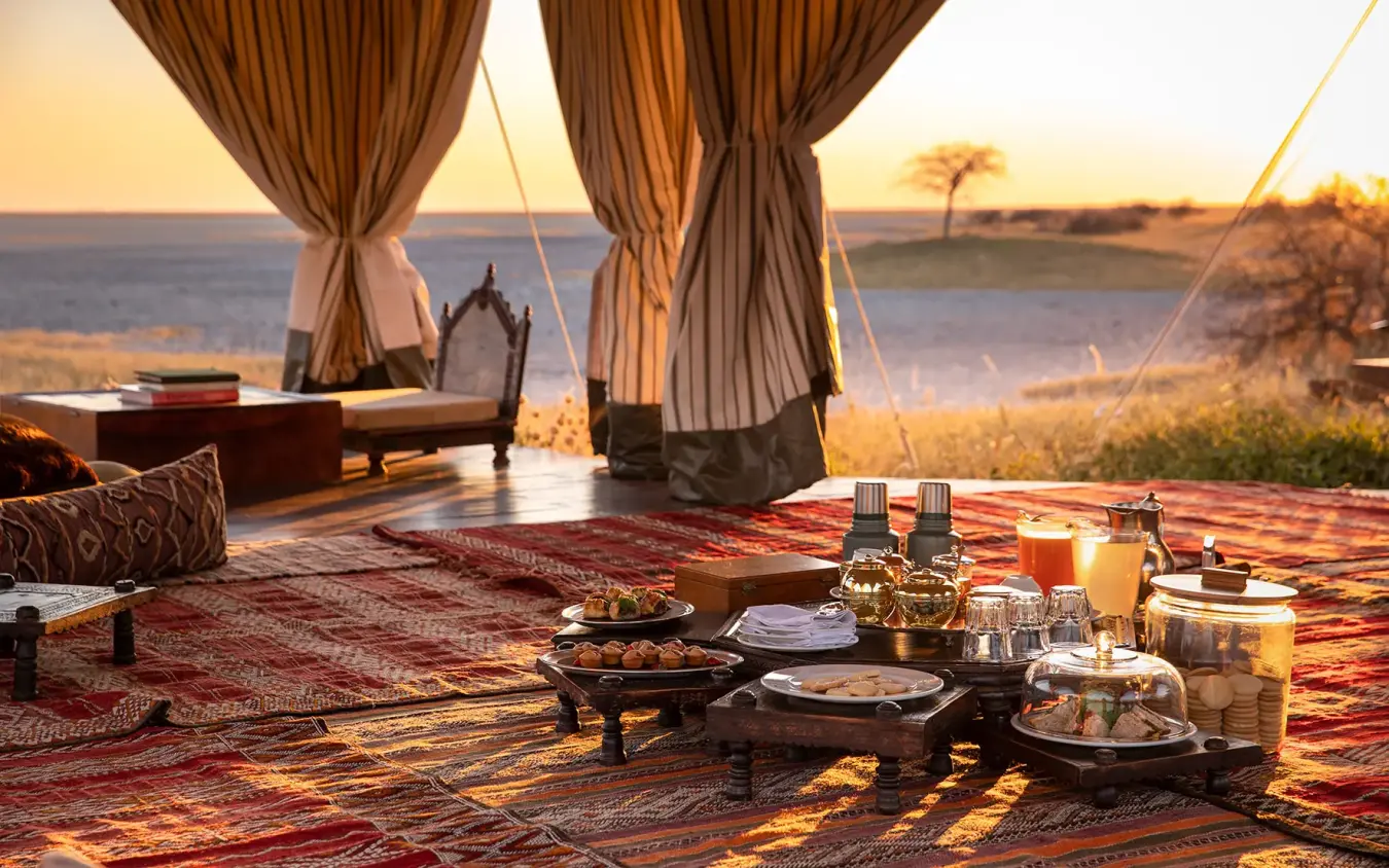 Safari camp dining setup overlooking water at sunset, San Camp, Makgadikgadi Pans, Botswana