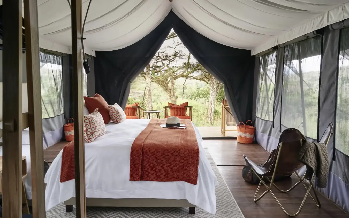 Luxury safari tent interior with canopy bed and savanna views through open sides, Sanctuary Crater Camp, Ngorongoro Crater, Tanzania