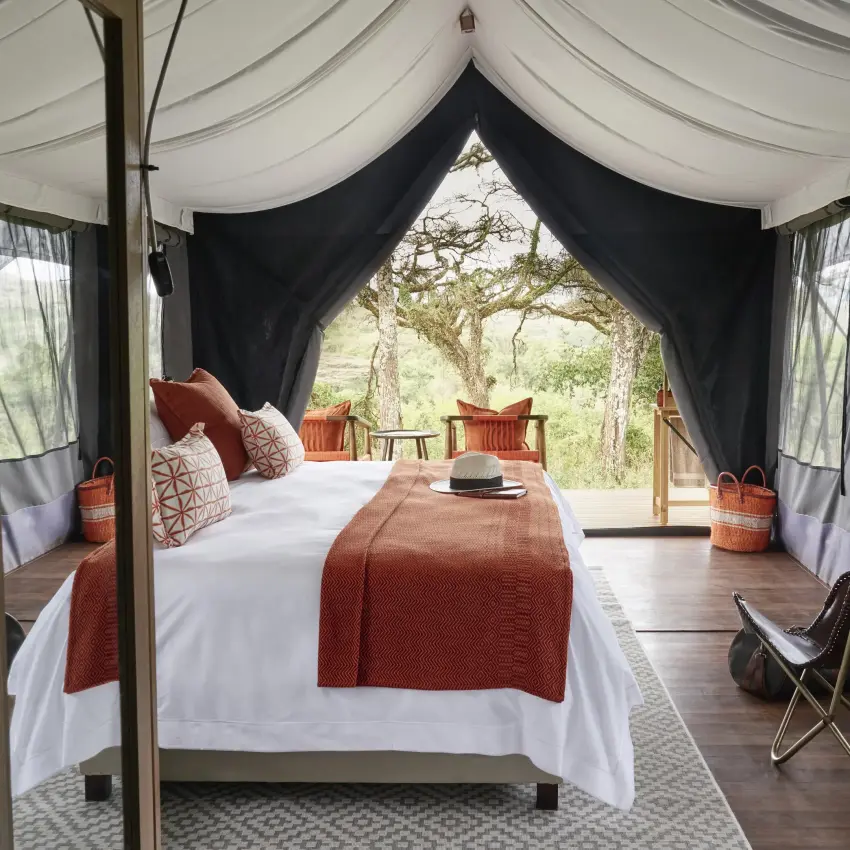 Safari tent bedroom with king bed overlooking acacia trees, Sanctuary Crater Camp, Ngorongoro Crater, Tanzania