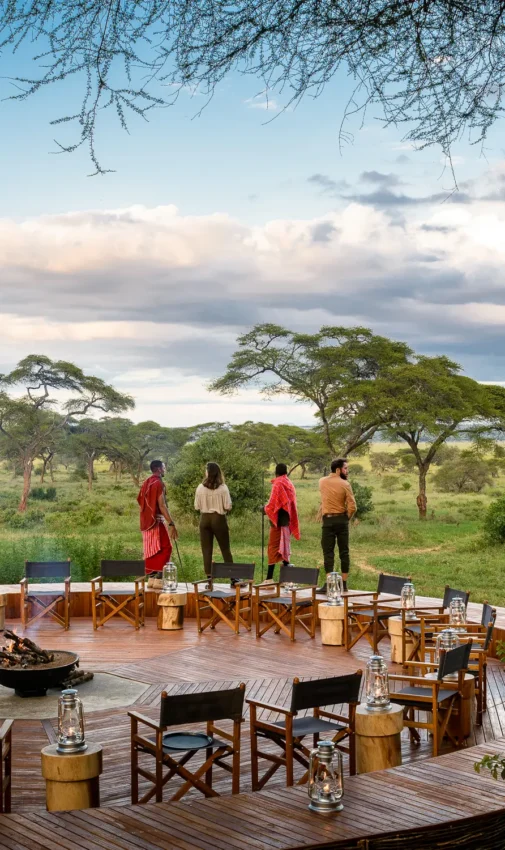 Outdoor dining deck with staff overlooking acacia woodland savanna