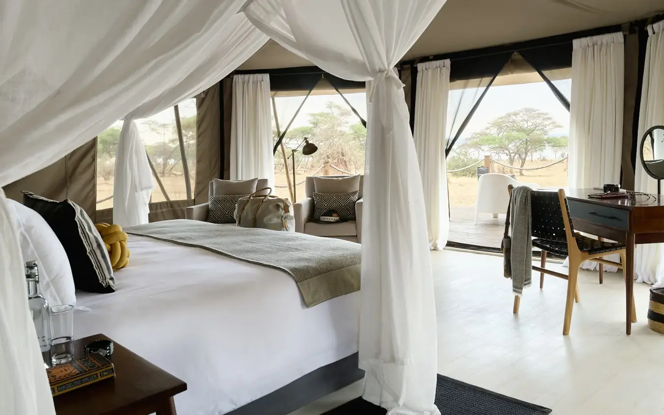 Luxury safari tent bedroom with canopy bed and savanna views through open windows, Swala, Tarangire National Park, Tanzania