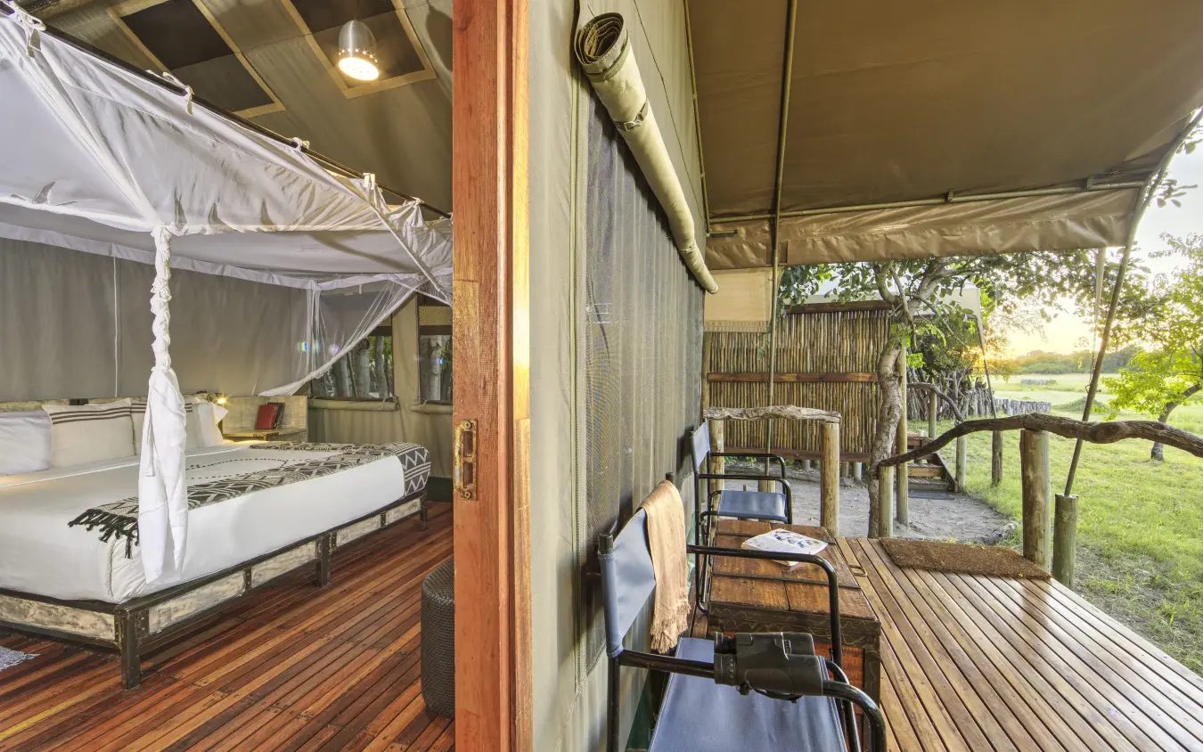 Luxury safari tent with four-poster bed and private veranda overlooking grassland, Sango Expedition Camp, Gonarezhou & Malilangwe, Zimbabwe