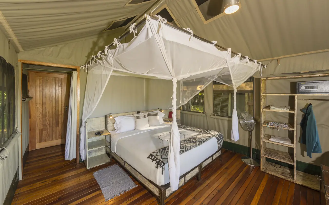 Four-poster canopy bed in safari lodge bedroom with wooden furnishings, Sango Expedition Camp, Gonarezhou & Malilangwe, Zimbabwe