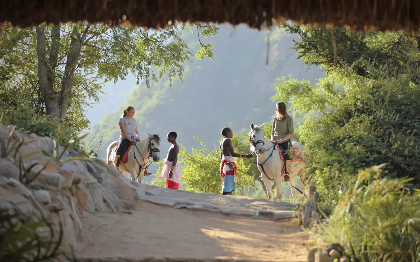 Guests horseback riding on shaded trail with mountain views, Sarara Camp, Northern Kenya, Kenya