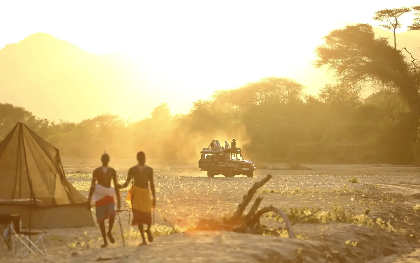 Guests by tent at golden hour near river, Sarara Camp, Northern Kenya, Kenya