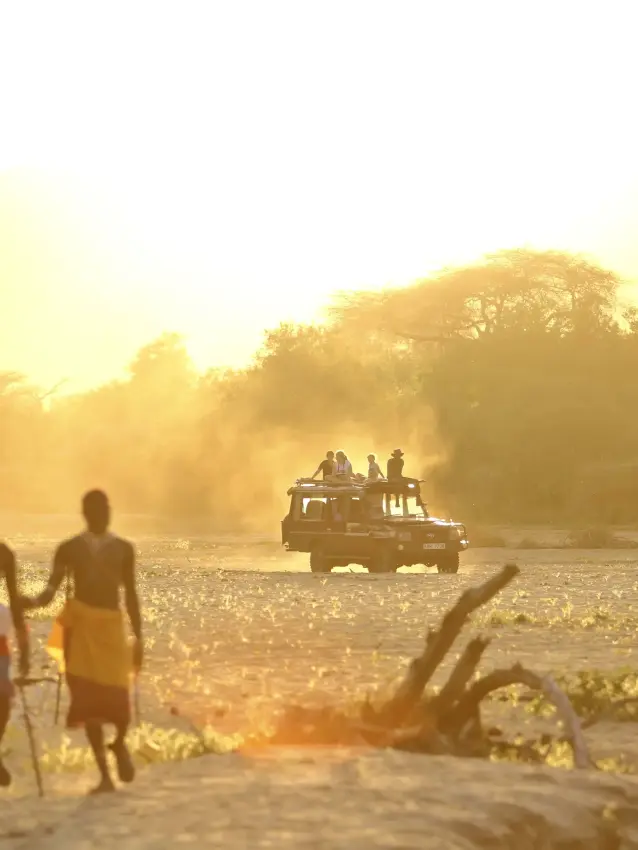 Guests by tent at golden hour near river, Sarara Camp, Northern Kenya, Kenya