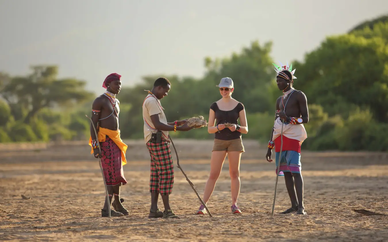 Guests interacting with local community members in savanna, Sarara Camp, Northern Kenya, Kenya