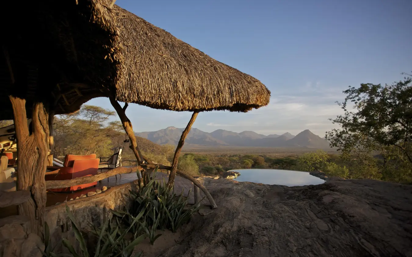 Thatched shelter overlooking waterhole and distant mountains, Sarara Camp, Northern Kenya, Kenya