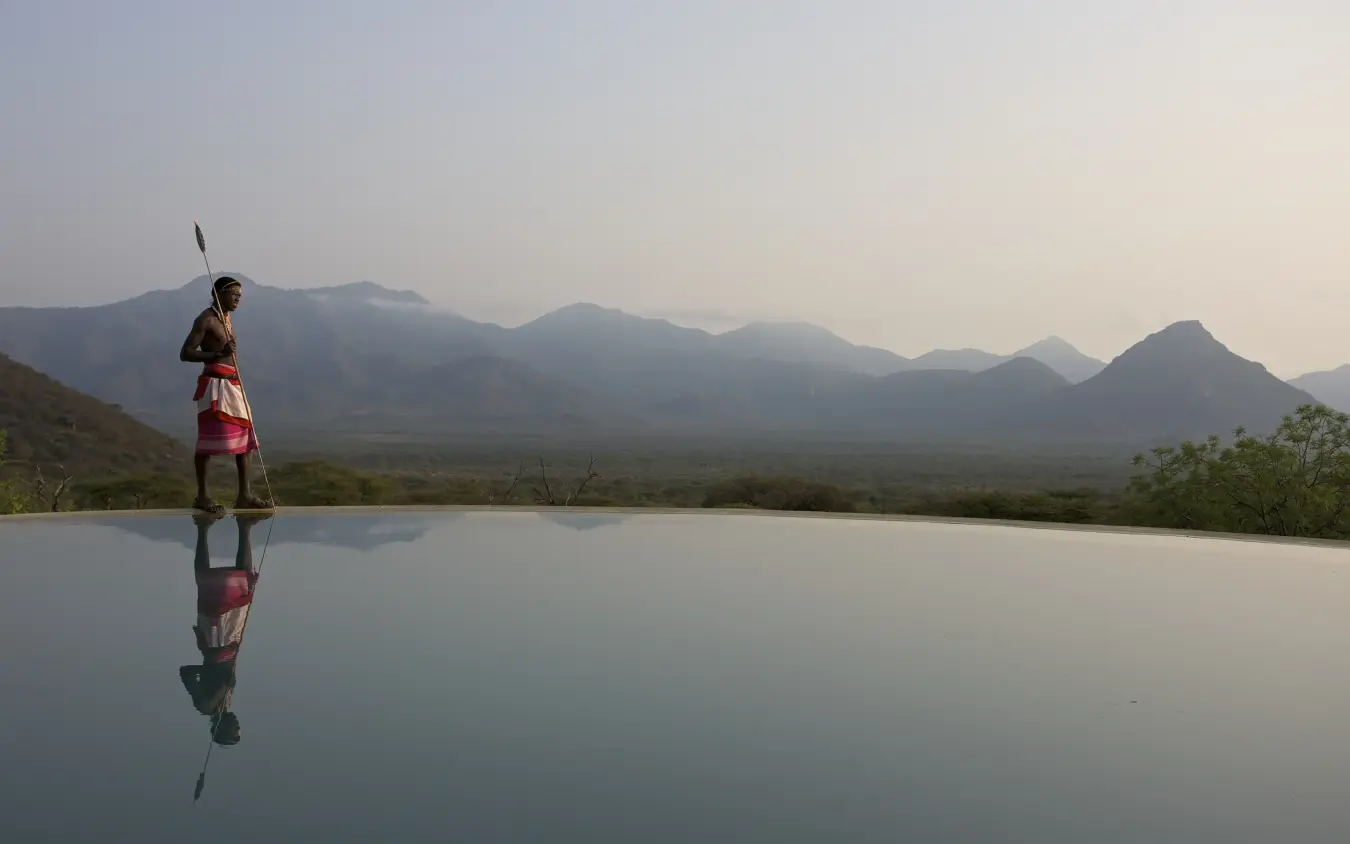 Person standing by infinity pool overlooking mountain landscape, Sarara Camp, Northern Kenya, Kenya