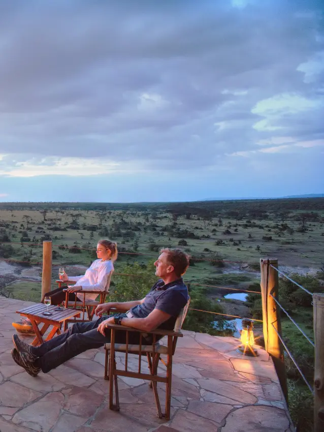 Guests relax by firepit on sunset viewing deck overlooking savanna, Eagle View Camp, Maasai Mara, Kenya