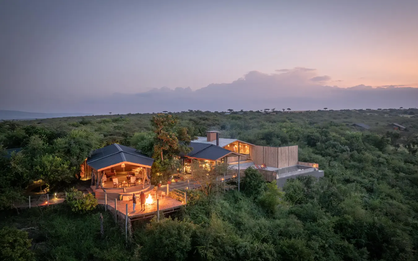 Illuminated lodge structures nestled in savanna landscape at dusk, Eagle View Camp, Maasai Mara, Kenya