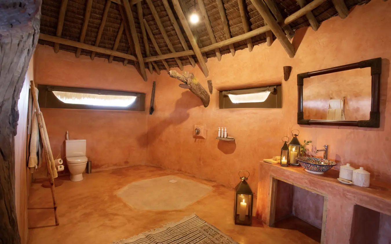 Thatched-roof bathroom with terracotta walls and ambient lighting, Saruni Rhino, Northern Kenya, Kenya