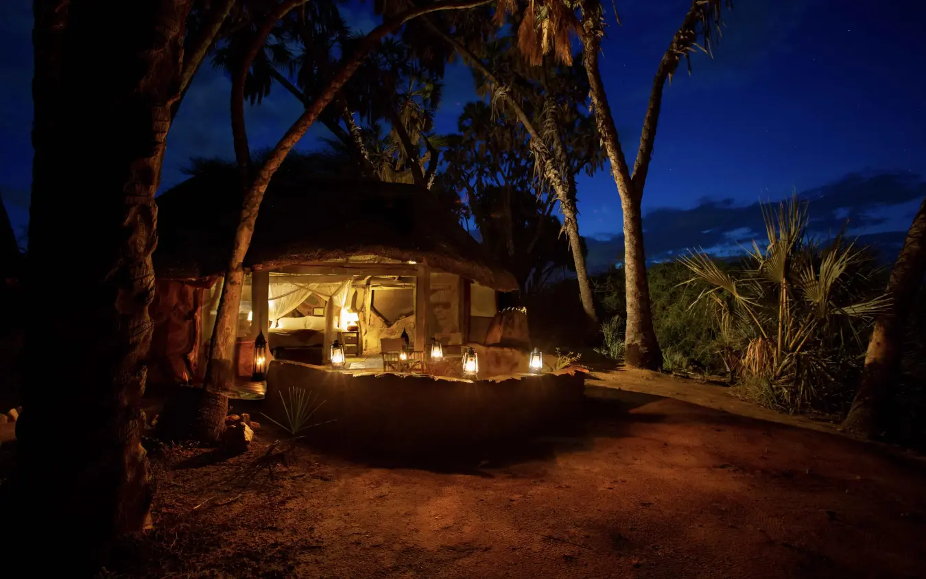 Illuminated safari tent beneath palm trees at dusk, Saruni Rhino, Northern Kenya, Kenya