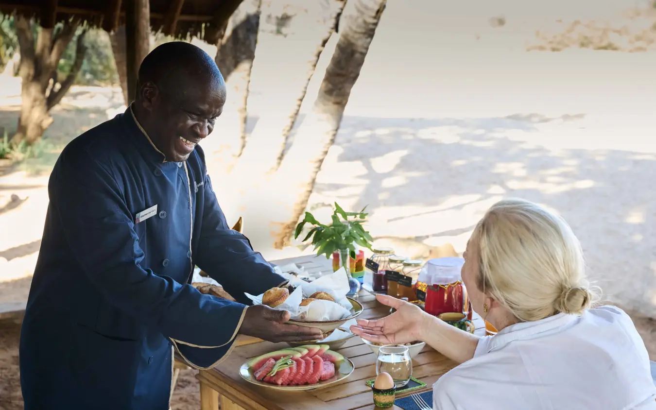 Staff member serving meal to guest at outdoor table with valley view, Saruni Rhino, Northern Kenya, Kenya