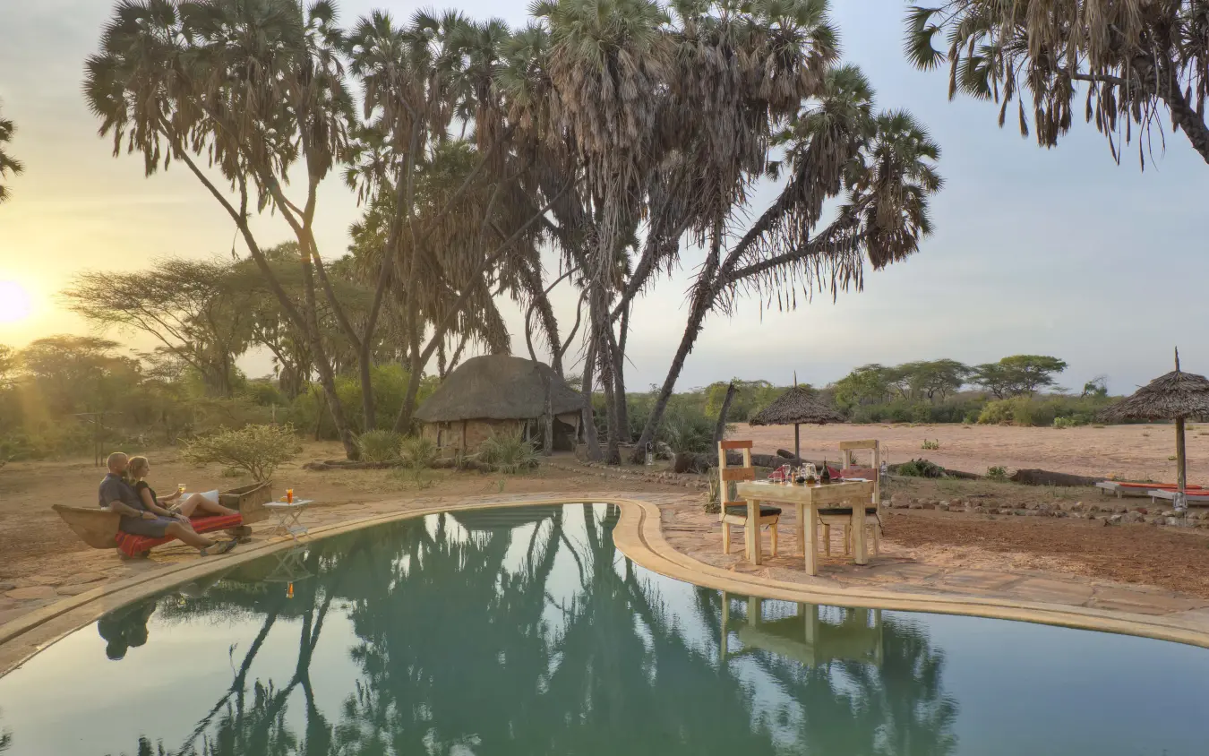 Pool reflecting acacia trees at safari lodge at sunset, Saruni Rhino, Northern Kenya, Kenya