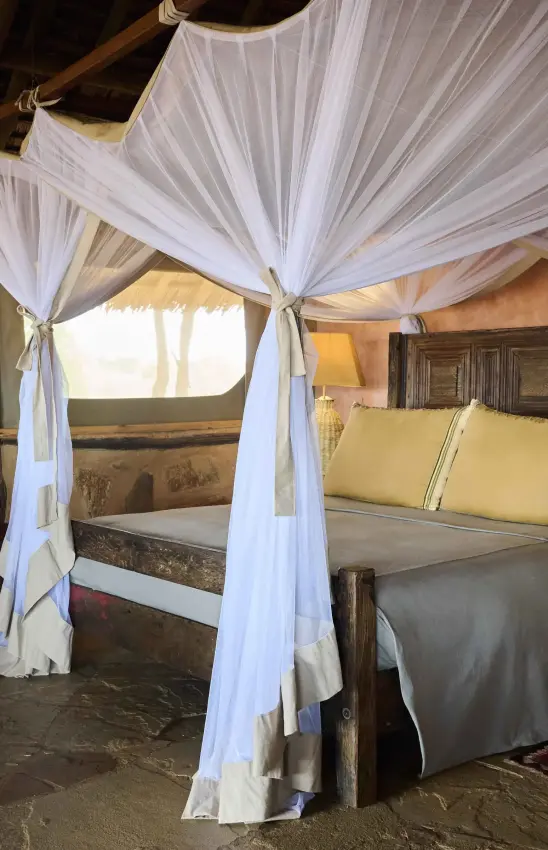 Four-poster bed with white gauze canopy in safari lodge bedroom, Saruni Rhino, Northern Kenya, Kenya