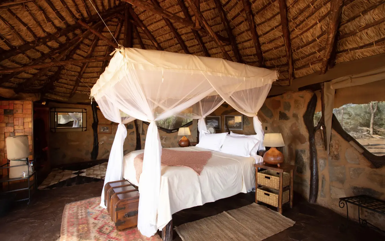 Luxury safari lodge bedroom with canopied bed and thatch roof interior, Saruni Rhino, Northern Kenya, Kenya