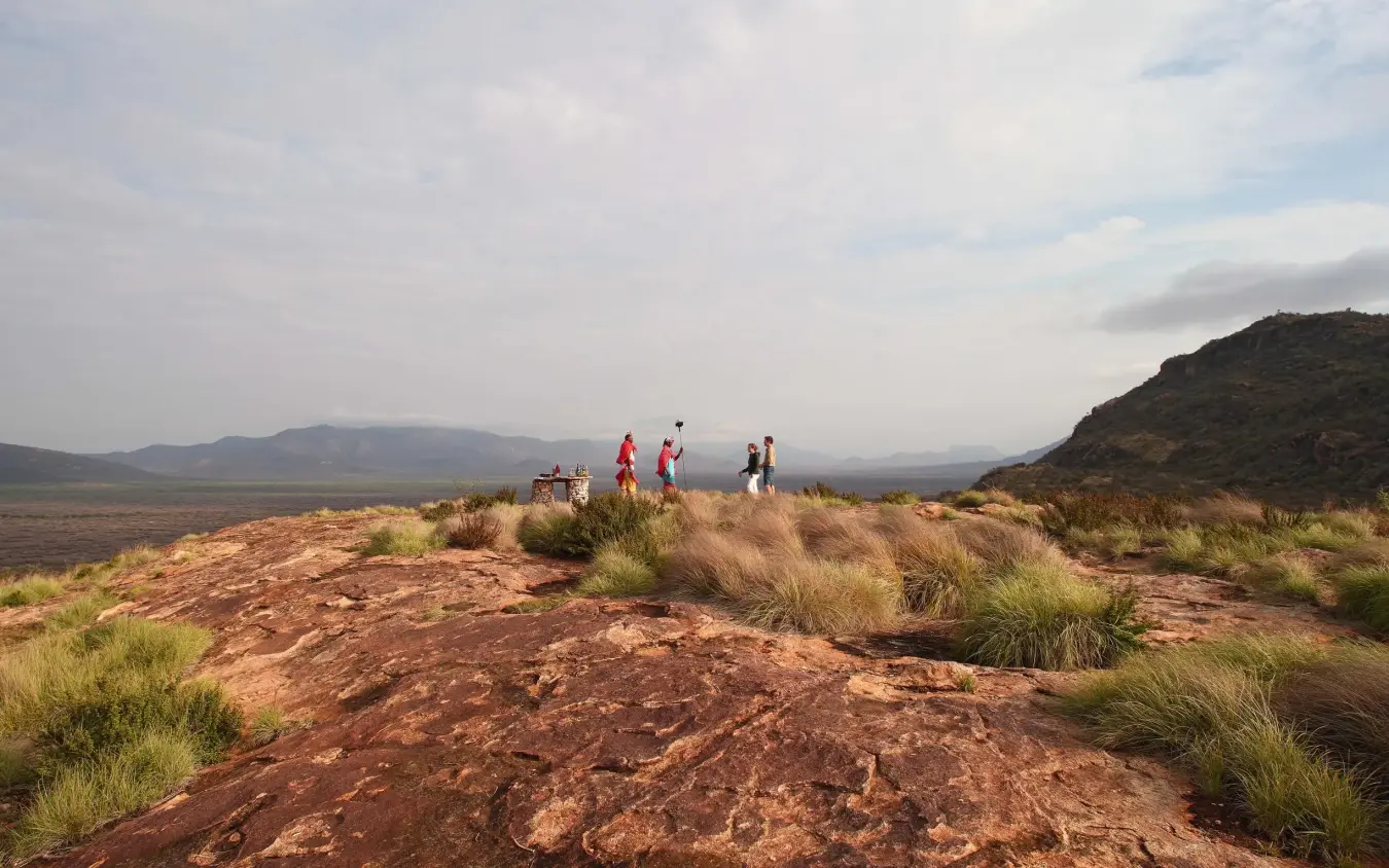 Hiking group stands on rocky outcrop in savanna landscape, Saruni Samburu, Samburu Reserve, Kenya